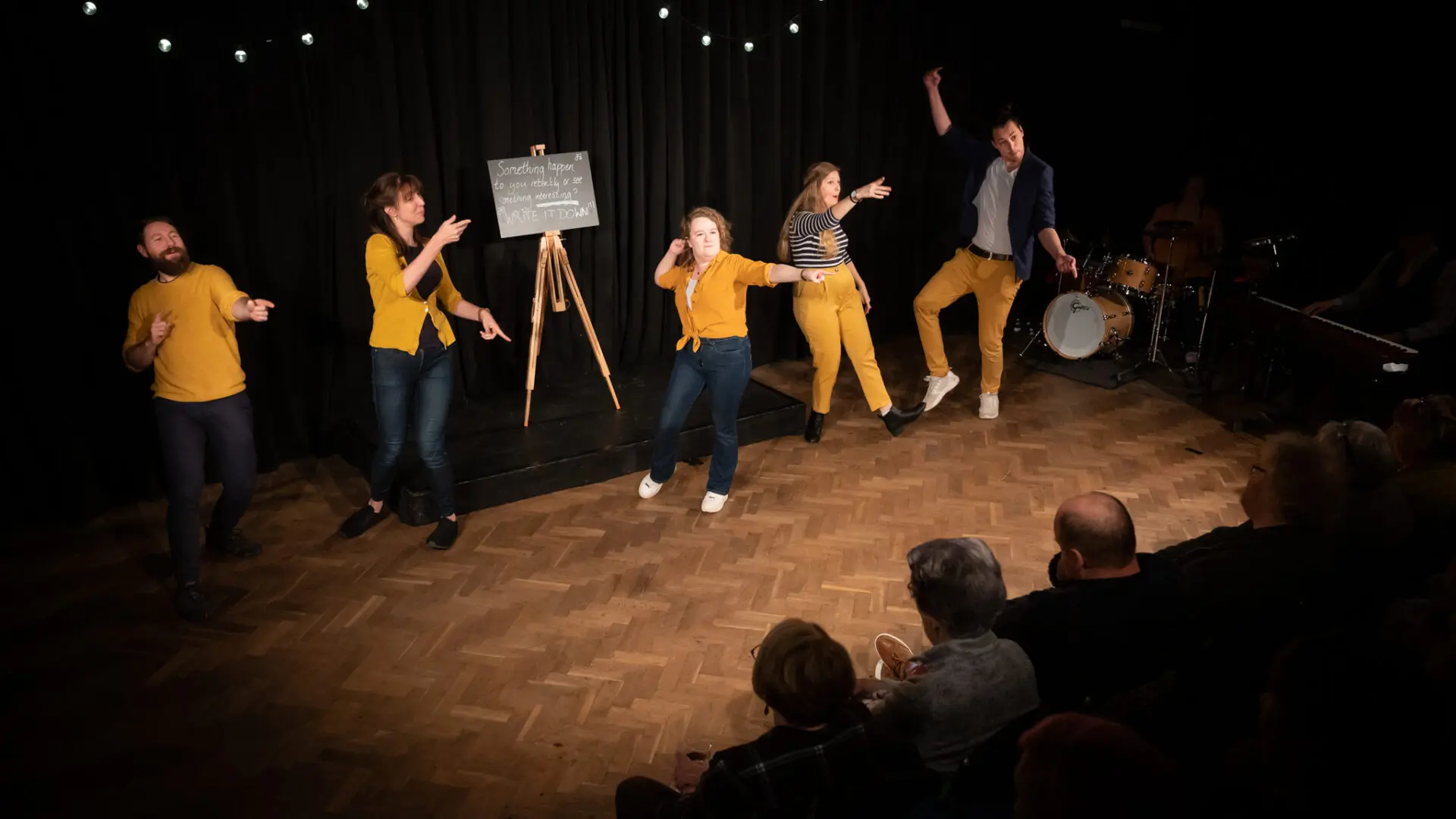 Different actors in yellow playing on stage