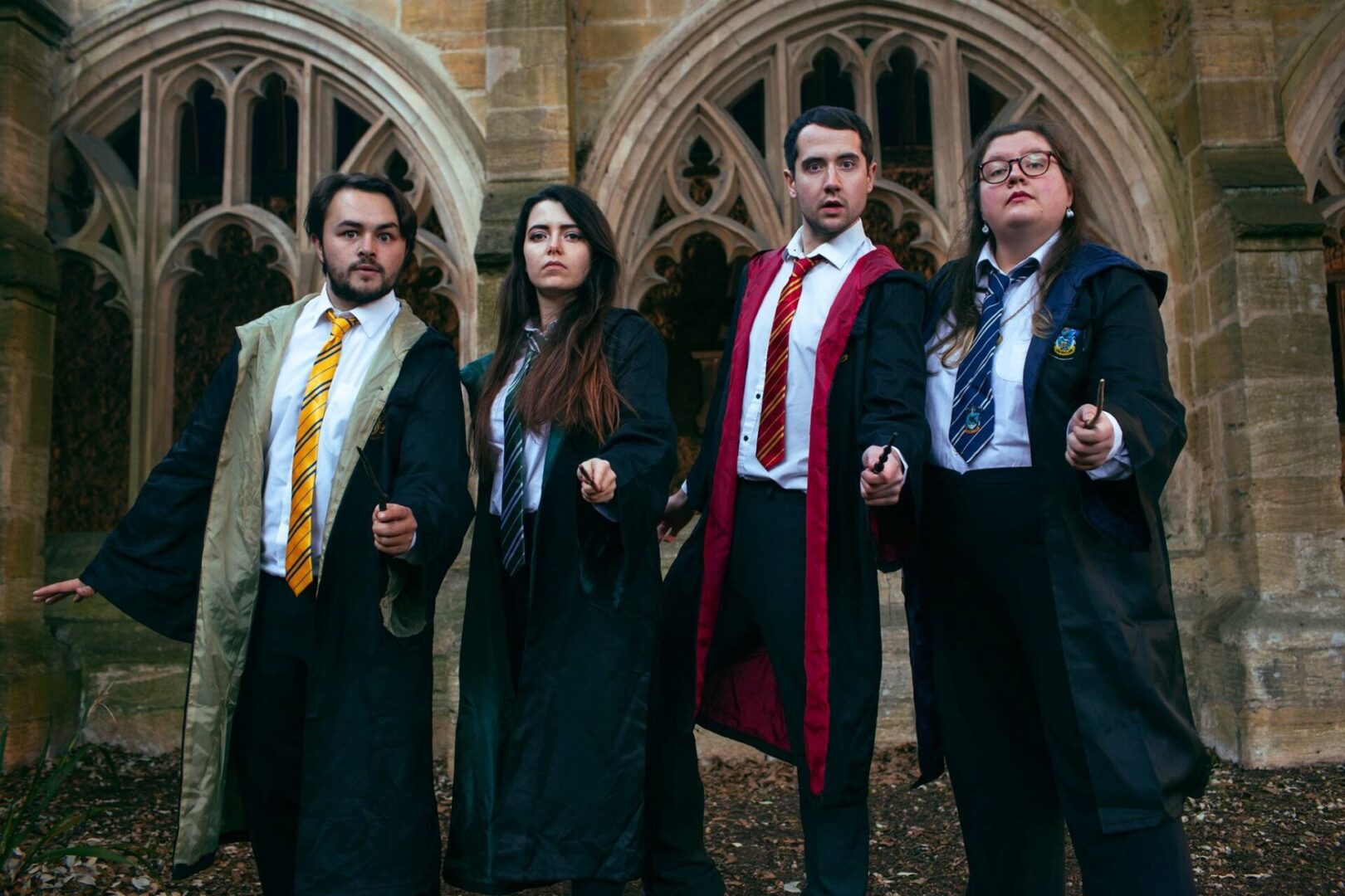 four actors wearing school ties brandishing magic wands