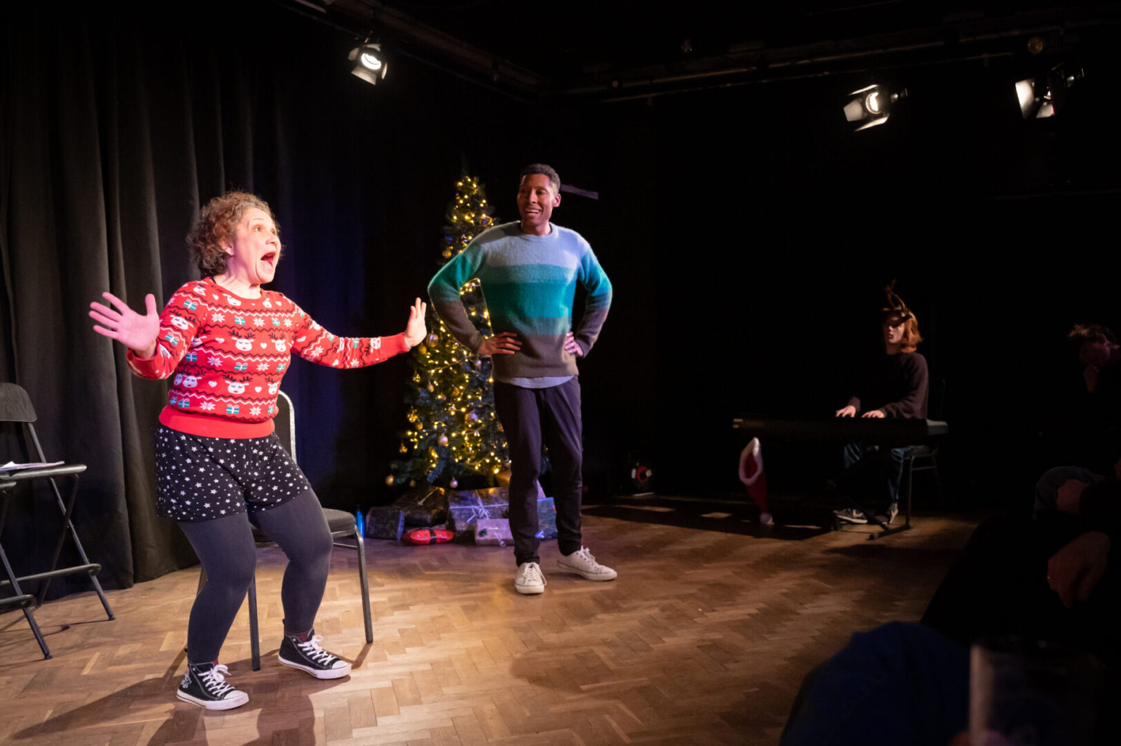 christmas at the bristol improv theatre. two performers (one woman, one man, in christmas jumpers acting in front of an auidence.