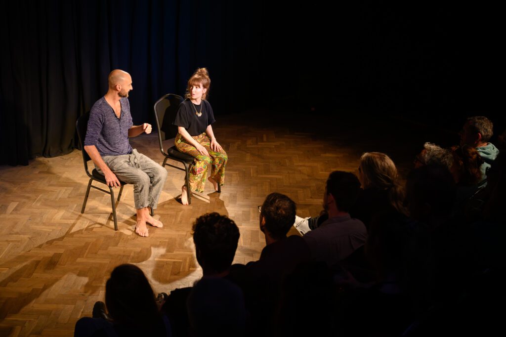 These Folk (Justin Brett and Susan Harrison) sat on chairs on stage at the Bristol Improv Theatre in front of an audience. 