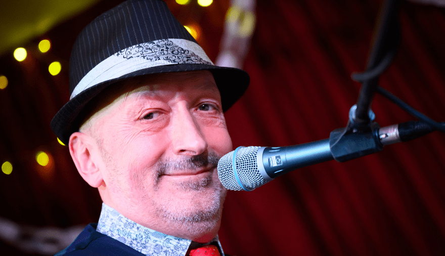 Close up picture of Ian Towers, smiling with a microphone in front of his face