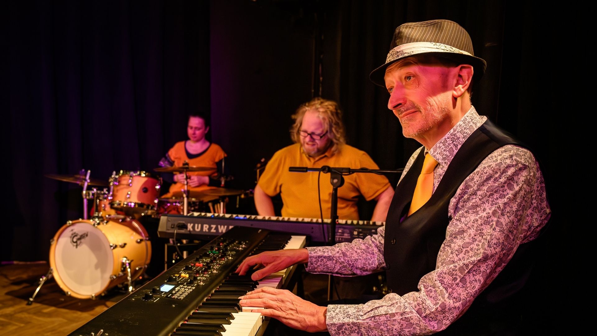 A man sits playing the keyboard whilst looking on to the stage