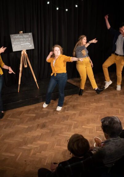 Different actors in yellow playing on stage