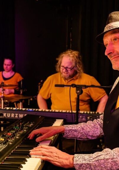 A man sits playing the keyboard whilst looking on to the stage